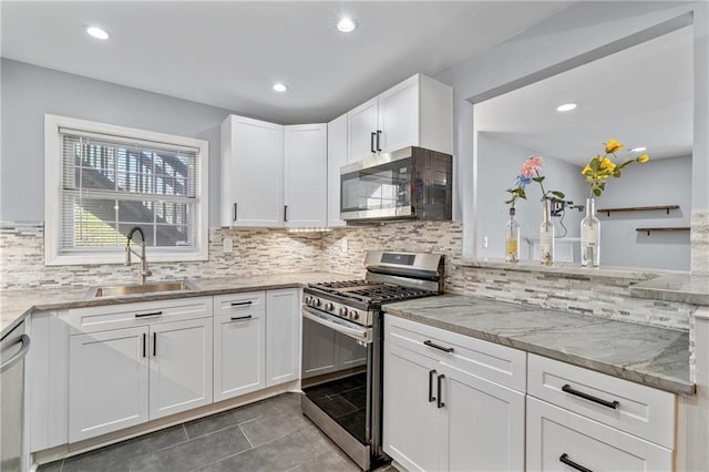 kitchen featuring light stone counters, stainless steel appliances, white cabinets, a sink, and tile patterned flooring