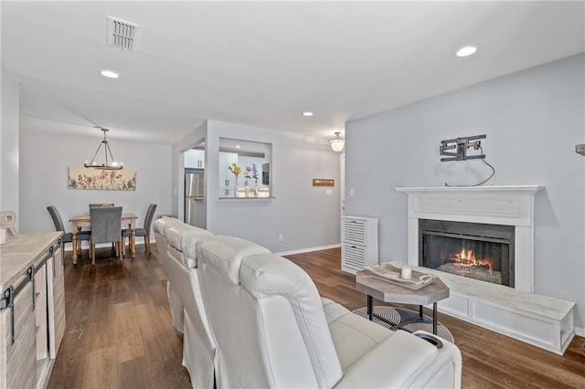 living room featuring dark wood-style floors, a lit fireplace, visible vents, and recessed lighting