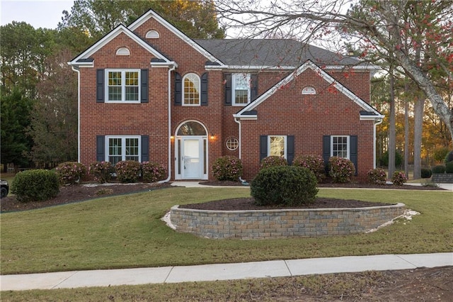 colonial inspired home featuring a front yard and brick siding