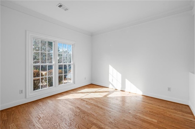 spare room featuring light wood finished floors, visible vents, baseboards, and ornamental molding