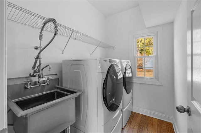 clothes washing area featuring washing machine and clothes dryer, laundry area, baseboards, and wood finished floors