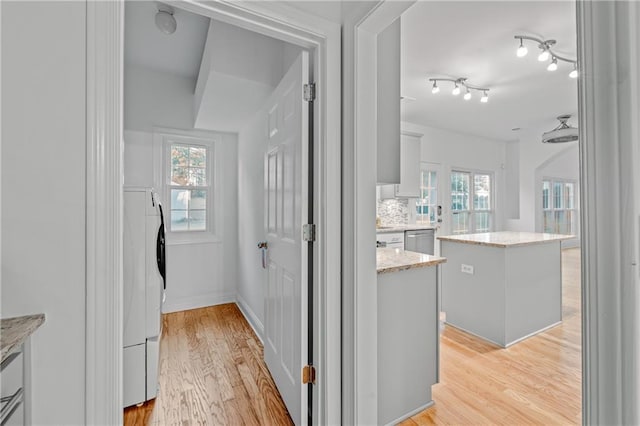 interior space with washer / dryer, a healthy amount of sunlight, and light wood-style floors