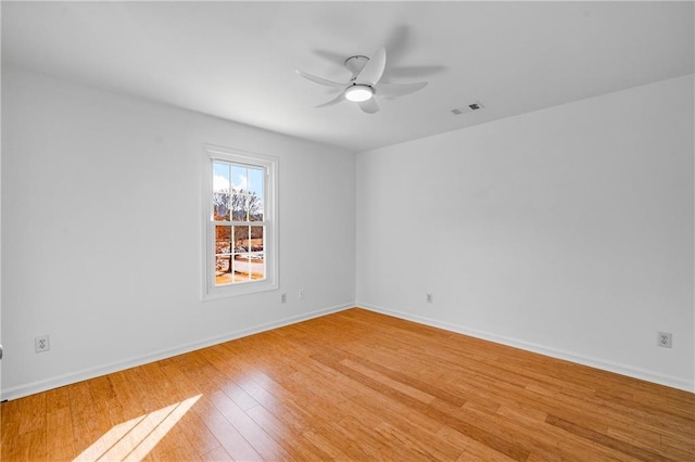 unfurnished room with light wood-style flooring, a ceiling fan, visible vents, and baseboards