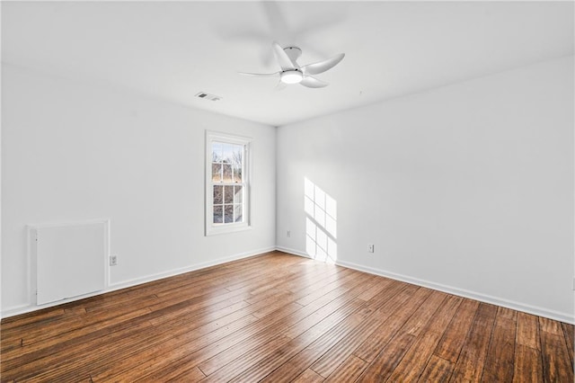 empty room with hardwood / wood-style flooring, a ceiling fan, visible vents, and baseboards