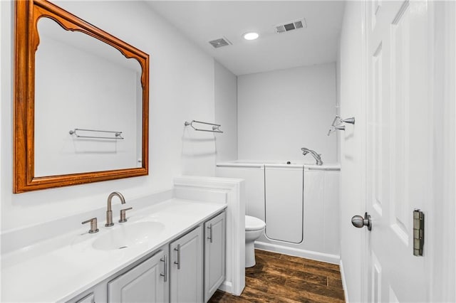 full bathroom featuring vanity, toilet, wood finished floors, and visible vents