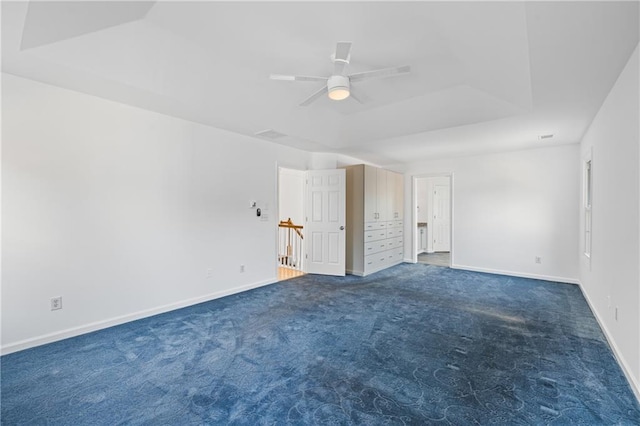 interior space featuring carpet, a raised ceiling, baseboards, and a ceiling fan