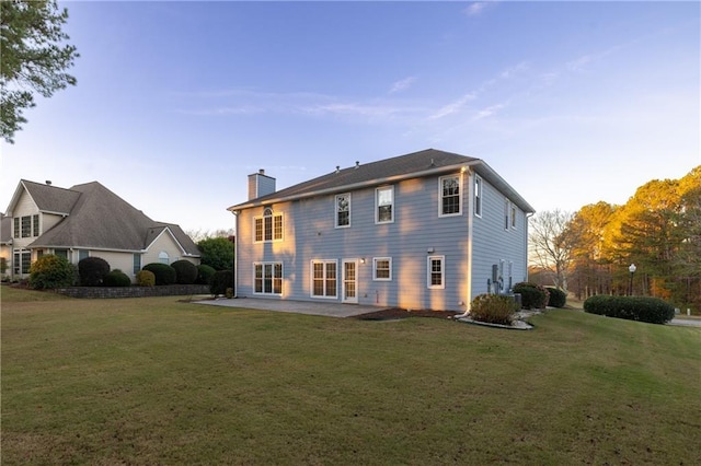 back of property with a patio, a yard, and a chimney