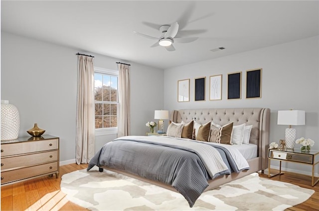 bedroom featuring visible vents, baseboards, wood finished floors, and a ceiling fan