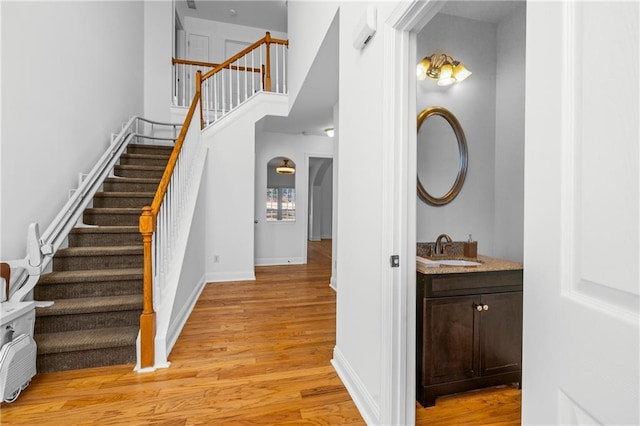 stairs with wood finished floors, baseboards, and a towering ceiling