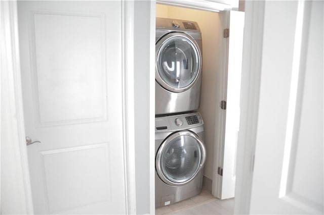 laundry area featuring light tile patterned flooring and stacked washer and clothes dryer