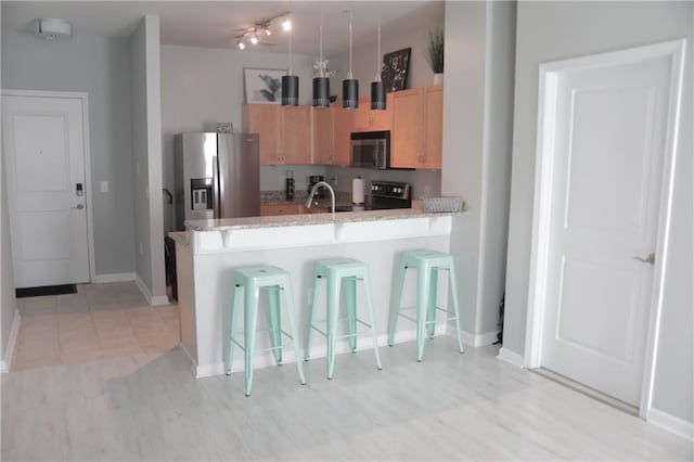 kitchen with kitchen peninsula, a breakfast bar, stainless steel appliances, sink, and light tile patterned floors