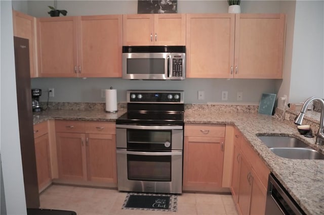 kitchen with light brown cabinetry, light stone counters, sink, and appliances with stainless steel finishes