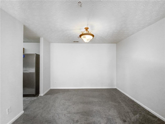 unfurnished room with dark colored carpet and a textured ceiling