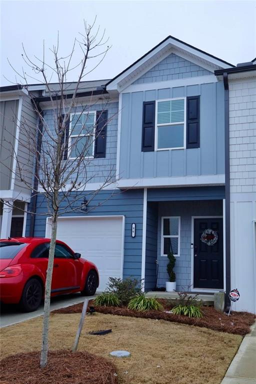 multi unit property featuring a garage and a front lawn