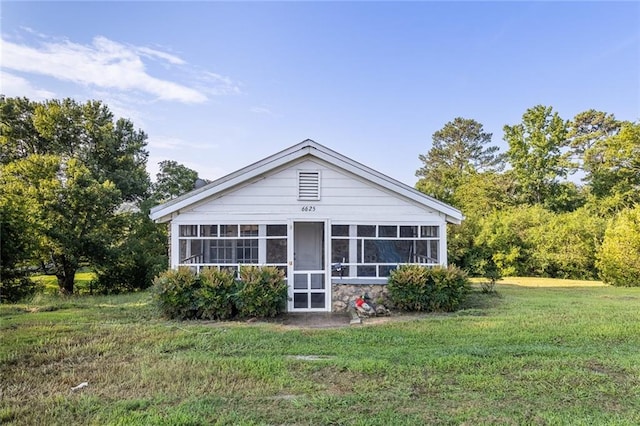 back of property featuring a sunroom and a lawn