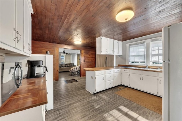 kitchen featuring white fridge, dark wood-type flooring, wood walls, wood ceiling, and ceiling fan