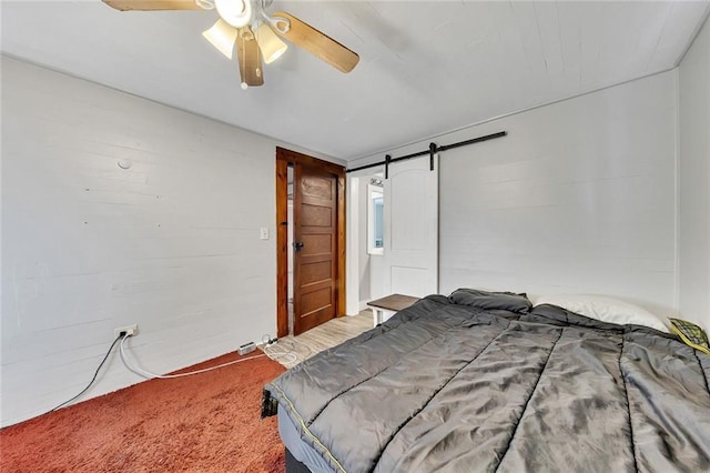 bedroom featuring carpet, a barn door, and ceiling fan