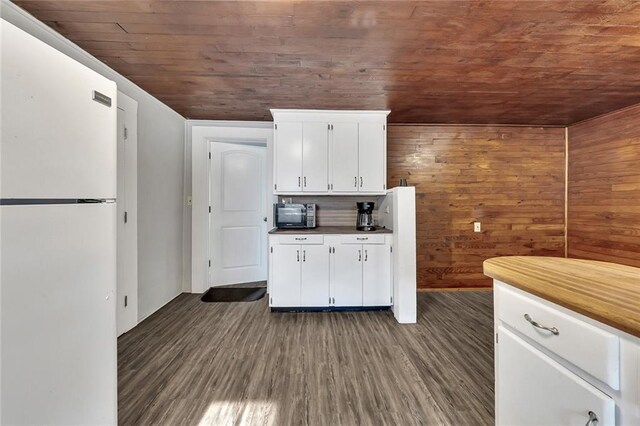 kitchen with white cabinets, white refrigerator, wood walls, wooden ceiling, and wood-type flooring