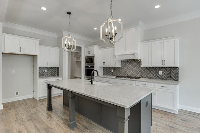 kitchen featuring white cabinets, a kitchen island with sink, sink, and pendant lighting