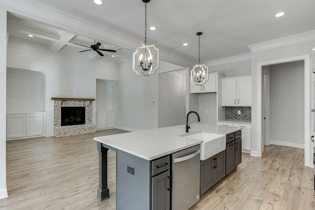 kitchen with a center island with sink, stainless steel dishwasher, beamed ceiling, coffered ceiling, and white cabinetry