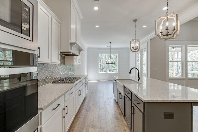 kitchen featuring a kitchen island with sink, sink, white cabinetry, and stainless steel appliances