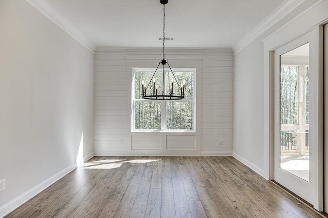 unfurnished dining area with a chandelier, ornamental molding, and hardwood / wood-style flooring