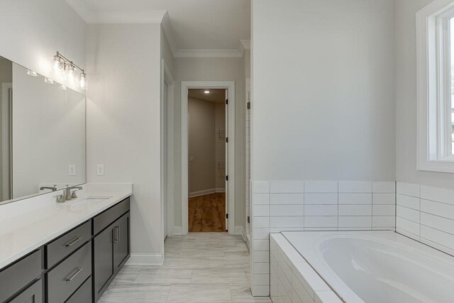 bathroom featuring tiled bath, a healthy amount of sunlight, crown molding, and vanity