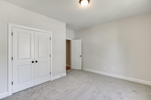 unfurnished bedroom featuring light colored carpet and a closet