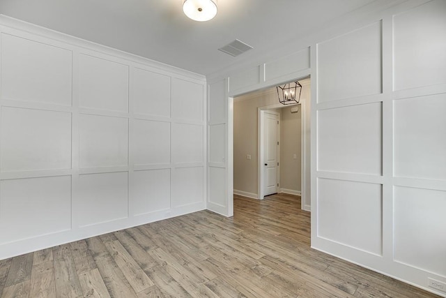 unfurnished room featuring light hardwood / wood-style flooring and a notable chandelier