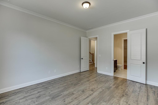 empty room featuring light wood-type flooring and crown molding