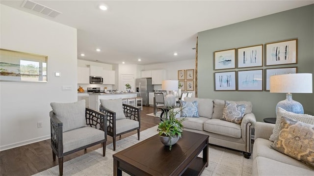 living area with recessed lighting, visible vents, and light wood finished floors