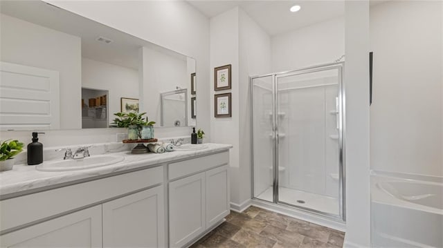 bathroom featuring double vanity, a garden tub, a shower stall, and a sink