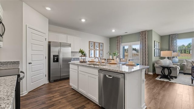 kitchen with dark wood-type flooring, appliances with stainless steel finishes, open floor plan, and a sink