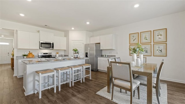 kitchen featuring a center island with sink, recessed lighting, appliances with stainless steel finishes, dark wood-type flooring, and white cabinets