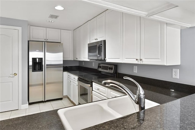 kitchen featuring appliances with stainless steel finishes, a sink, white cabinetry, light tile patterned floors, and visible vents