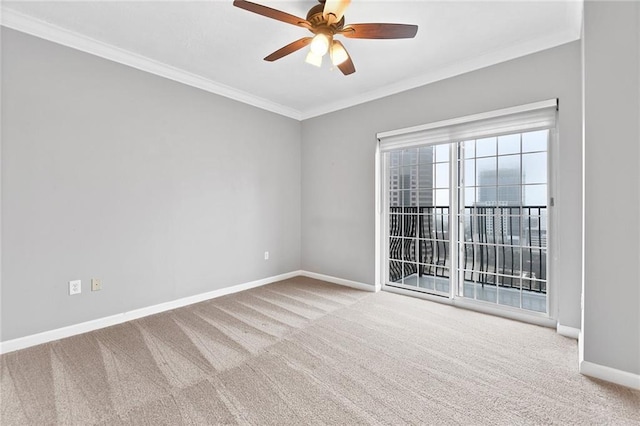 spare room with carpet floors, crown molding, baseboards, and ceiling fan