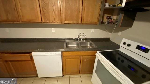kitchen featuring dark countertops, light tile patterned flooring, a sink, and white appliances