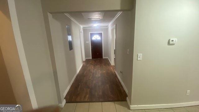 corridor featuring wood finished floors, ornamental molding, and baseboards