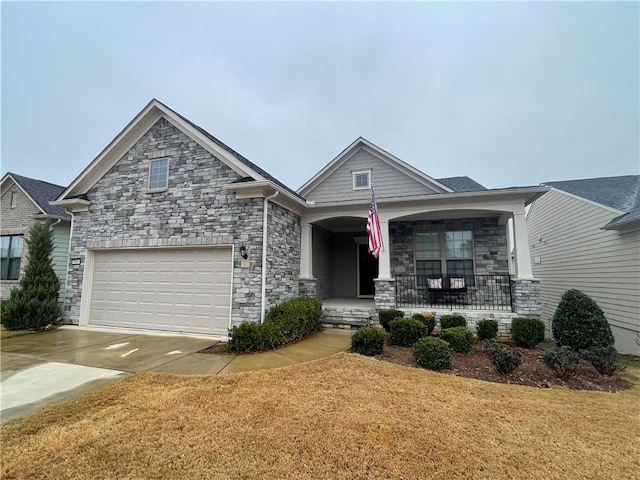 craftsman-style home with a garage, covered porch, concrete driveway, and a front yard