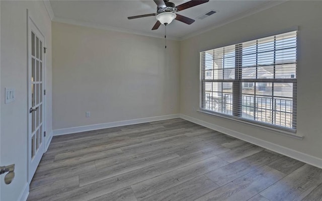 spare room featuring visible vents, ornamental molding, ceiling fan, wood finished floors, and baseboards