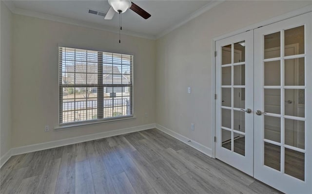 spare room with wood finished floors, visible vents, baseboards, french doors, and crown molding