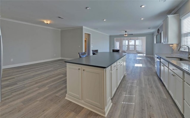 kitchen with a sink, visible vents, light wood-style floors, open floor plan, and baseboards