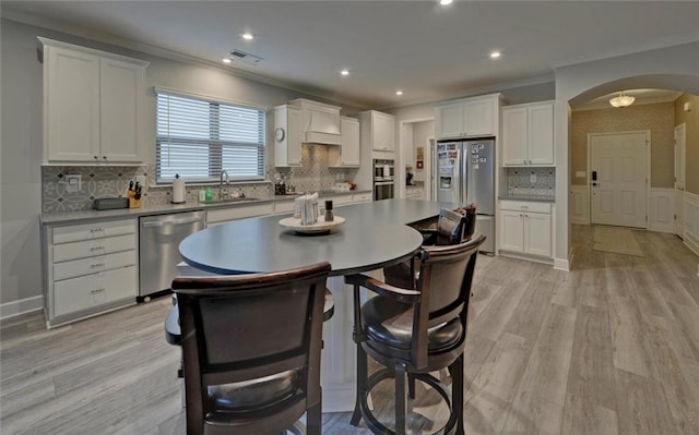 kitchen featuring white cabinets, arched walkways, stainless steel appliances, and a sink