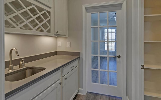 kitchen featuring ceiling fan, a sink, dark wood finished floors, and white cabinets