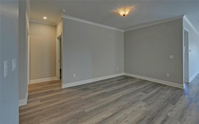 spare room featuring baseboards, wood finished floors, and ornamental molding