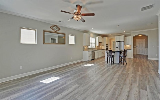 kitchen with arched walkways, visible vents, appliances with stainless steel finishes, white cabinetry, and a kitchen bar