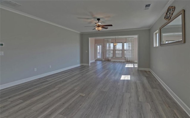 empty room featuring ceiling fan, wood finished floors, visible vents, baseboards, and ornamental molding