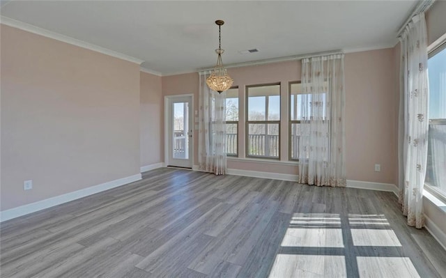 unfurnished room with plenty of natural light, crown molding, baseboards, and wood finished floors