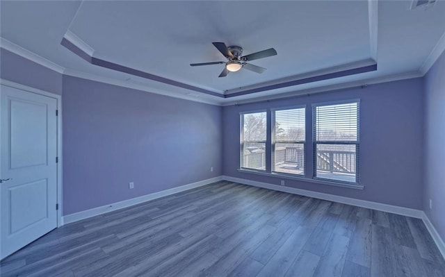 unfurnished room with crown molding, a tray ceiling, and wood finished floors