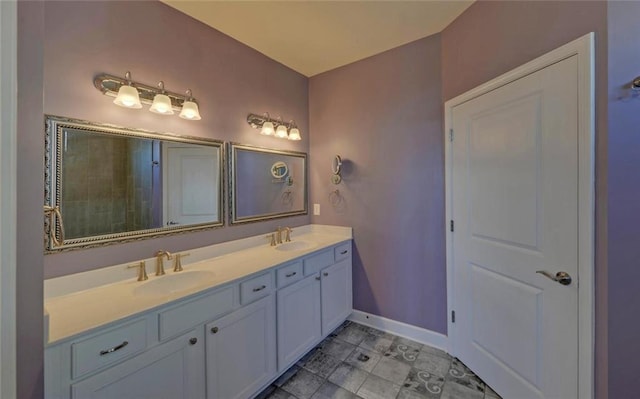 full bath with double vanity, a sink, and baseboards